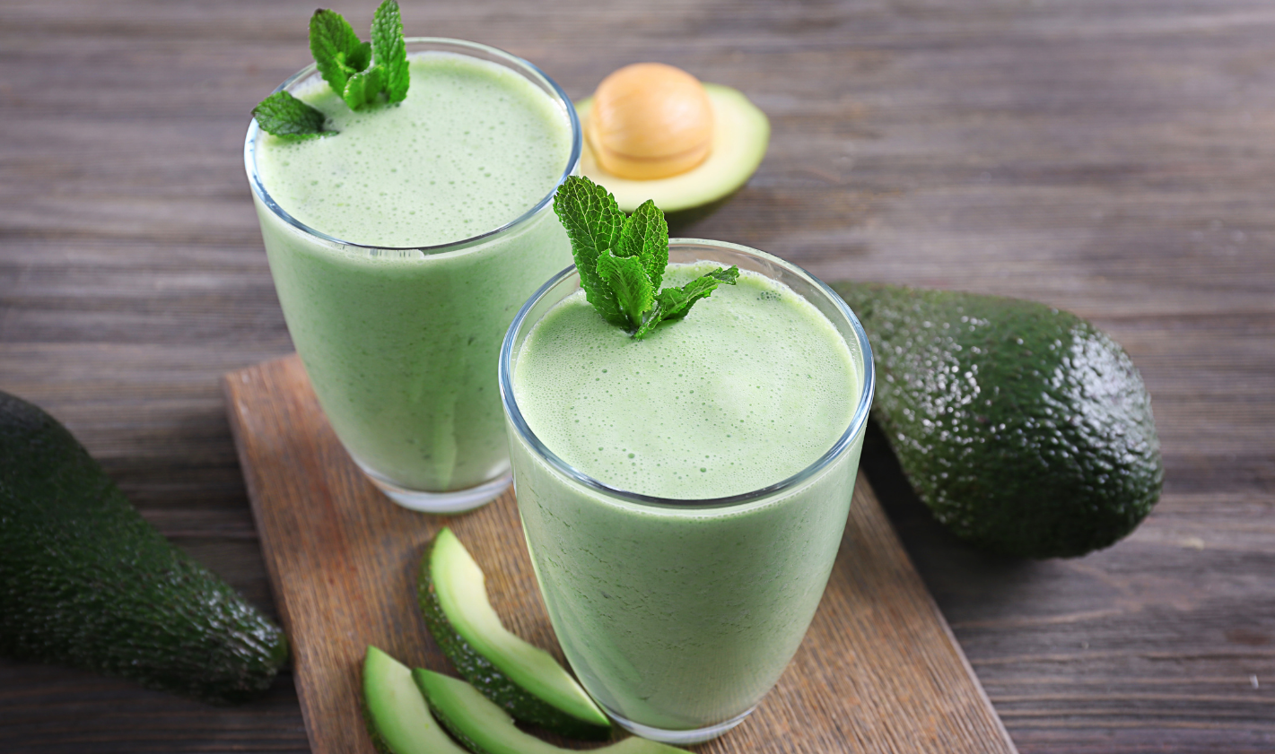 Two glasses of avocado green smoothie with mint sprig garnish