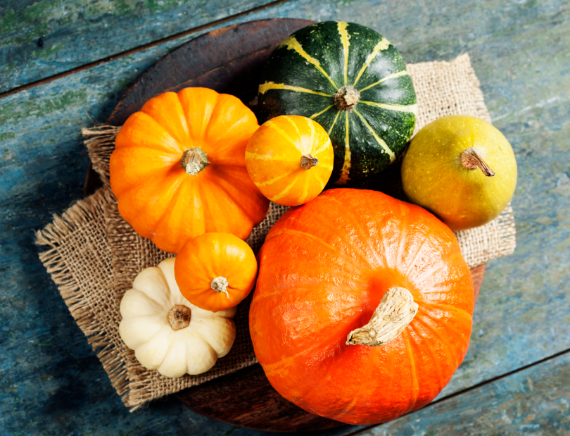 Over view of a pile of different pumpkins sitting on a distressed picnic table.