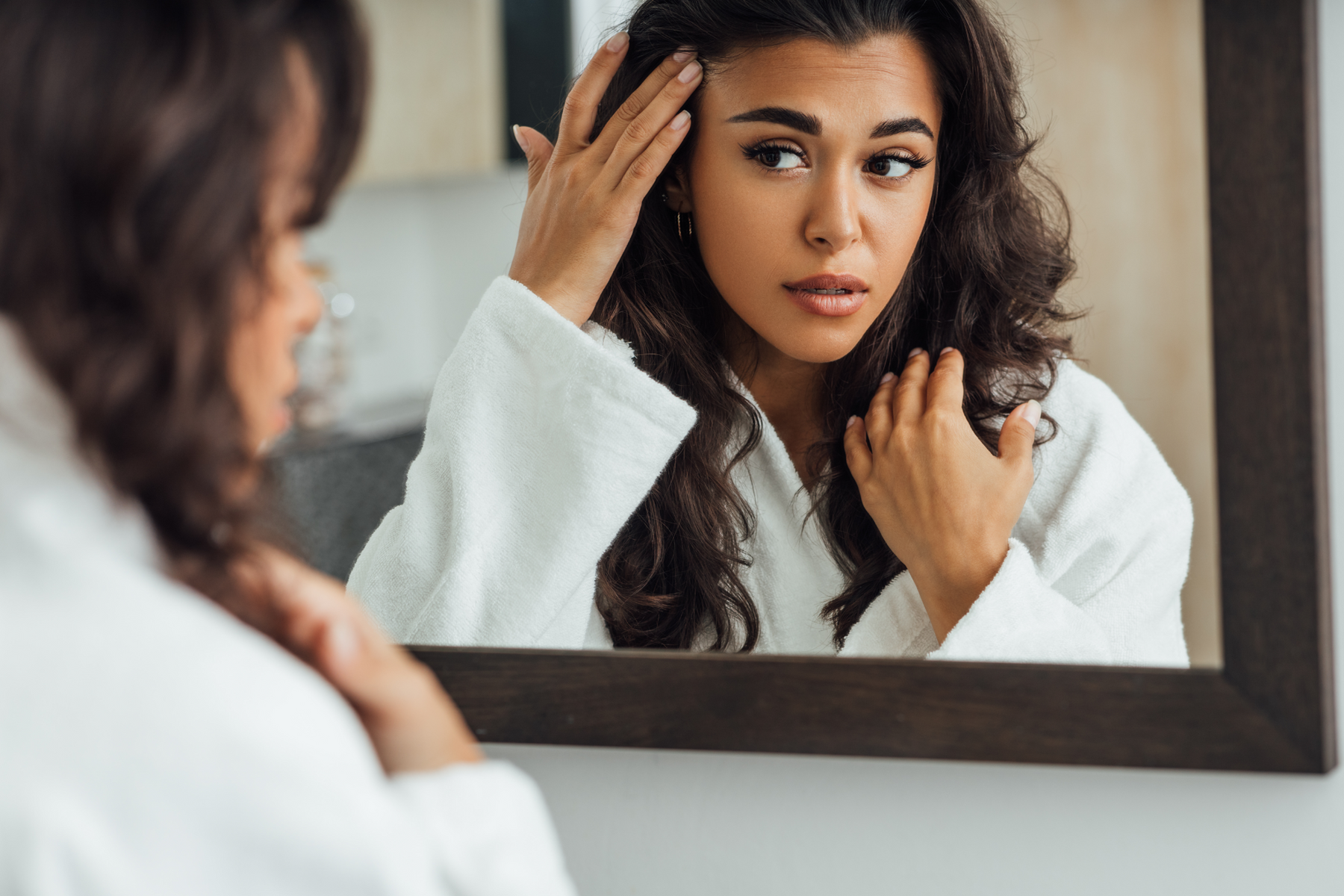 Woman looking at skin in mirror