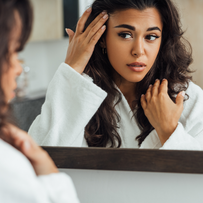 Woman looking at skin in mirror