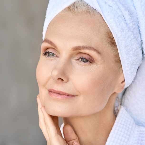 Older woman in a robe touching her face