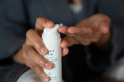 A woman dispensing a blue-coloured probiotic face cream into her hand.