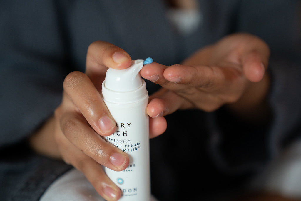 A woman dispensing a blue-coloured probiotic face cream into her hand.